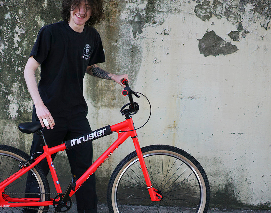 Man standing with a Thruster bike, highlighting bicycle clearance deals and discount bikes available at Mendham Bikes' online bicycle sales.
