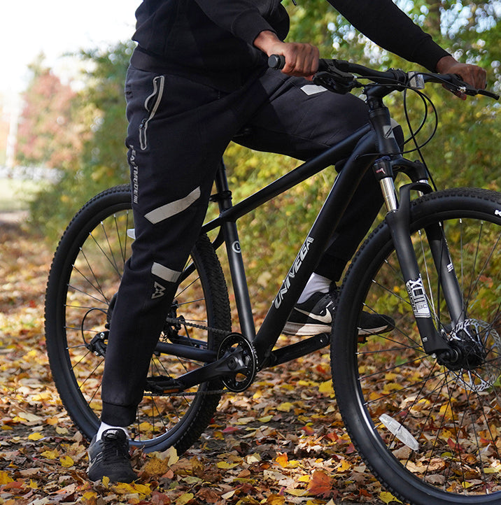 Person riding a black mountain bike through autumn leaves, showcasing clearance discount bikes, and online bicycle sales at Mendham Bikes.